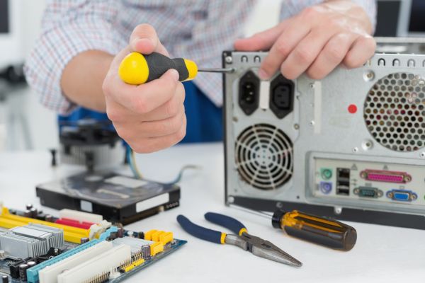 Young technician working on broken computer in his office